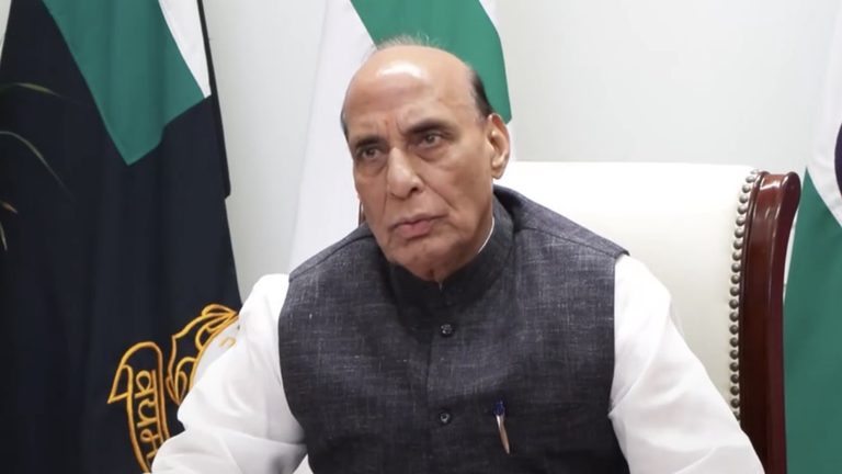 राजनाथ सिंह एक औपचारिक बैठक में बैठे हुए हैं, जिनके पीछे भारतीय ध्वज के रंग का प्रतीक चिन्ह दिखाई दे रहा है।